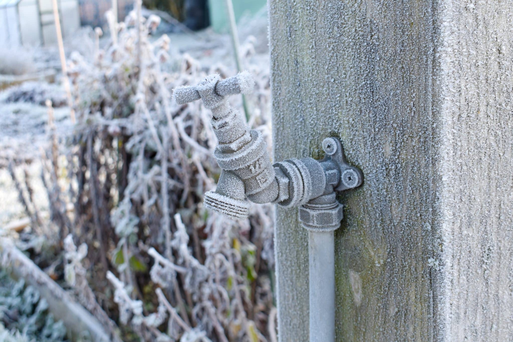 Outdoor plumbing and pipes frozen over due to winter frost, indicating the need for pre-winter maintenance.