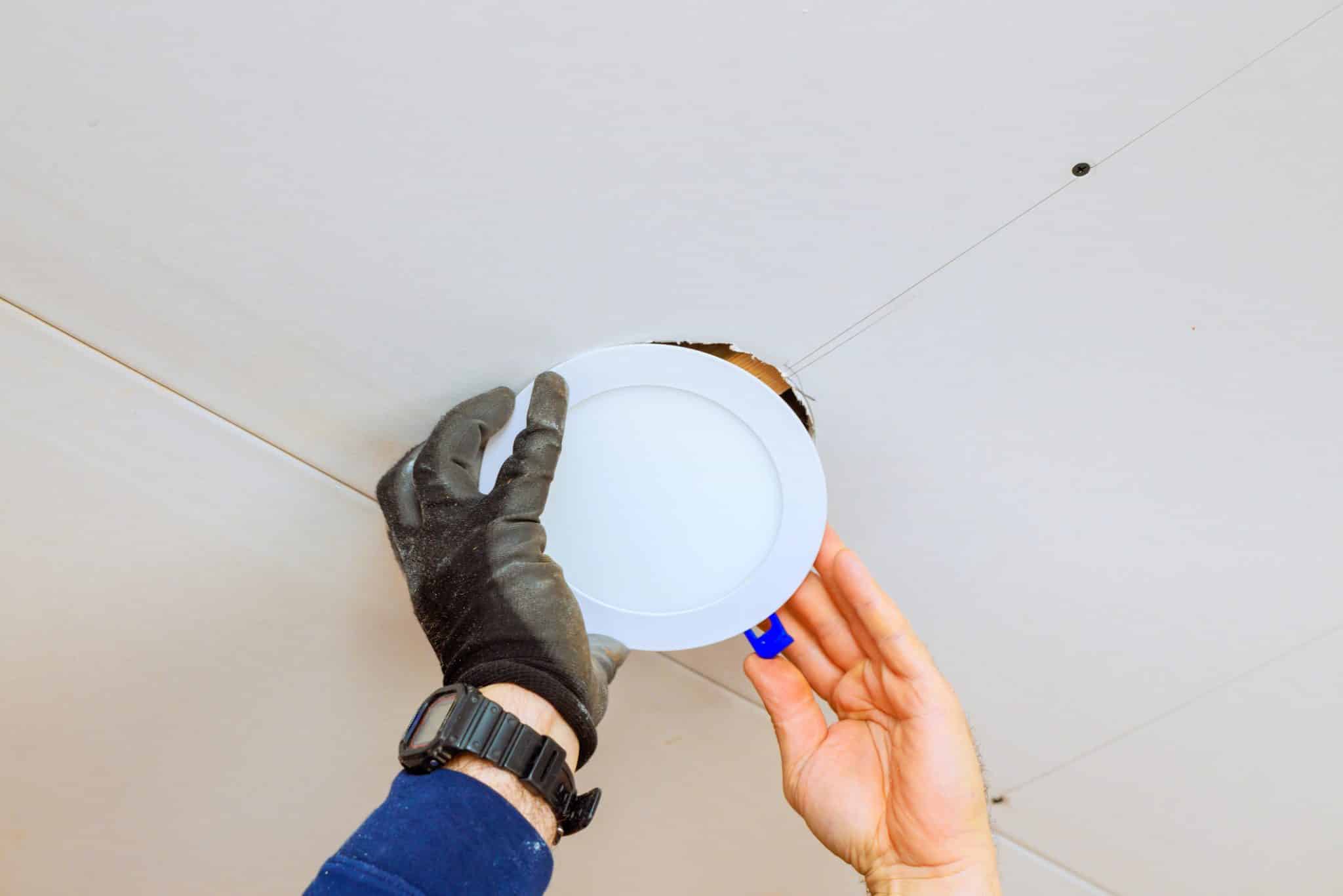 Electrician installing recessed LED light fixture during an LED retrofit for a commercial building.